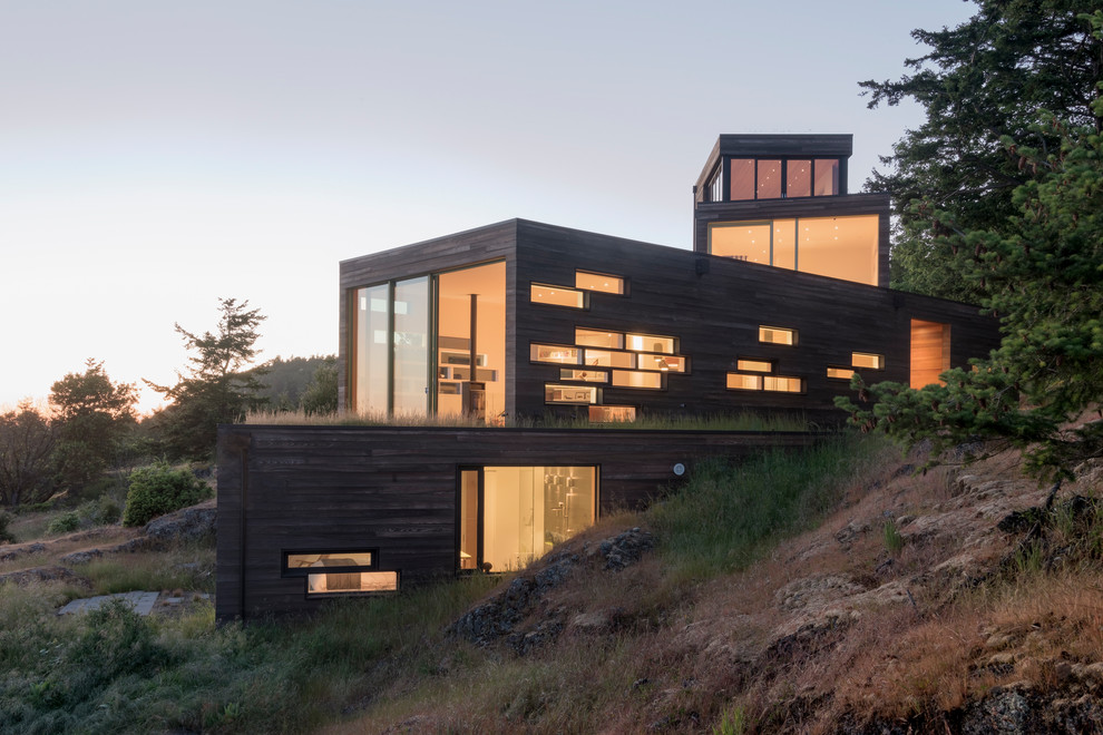 Стильный дизайн: трехэтажный, деревянный, коричневый частный загородный дом среднего размера в современном стиле с плоской крышей и зеленой крышей - последний тренд