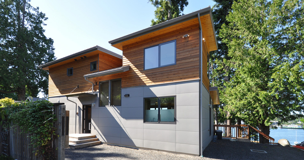 Пример оригинального дизайна: маленький, двухэтажный, серый дом в современном стиле с облицовкой из ЦСП и односкатной крышей для на участке и в саду