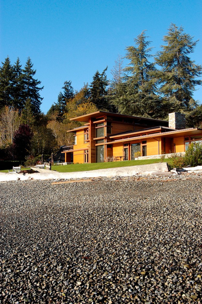 Esempio della facciata di una casa grande marrone contemporanea a due piani con rivestimento in legno e tetto a capanna