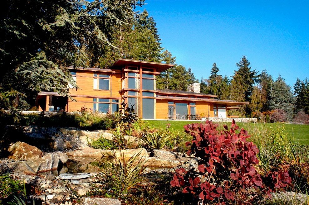 На фото: большой, двухэтажный, деревянный, коричневый дом в современном стиле с двускатной крышей