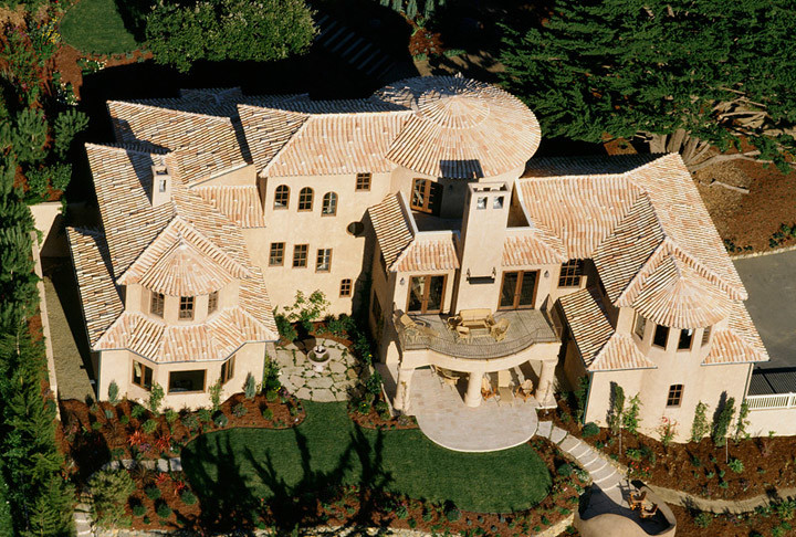 Example of a huge tuscan beige three-story stucco house exterior design in San Diego with a hip roof and a tile roof