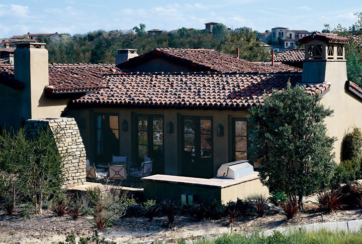 Cette photo montre une grande façade de maison beige méditerranéenne en stuc de plain-pied avec un toit à deux pans et un toit en tuile.