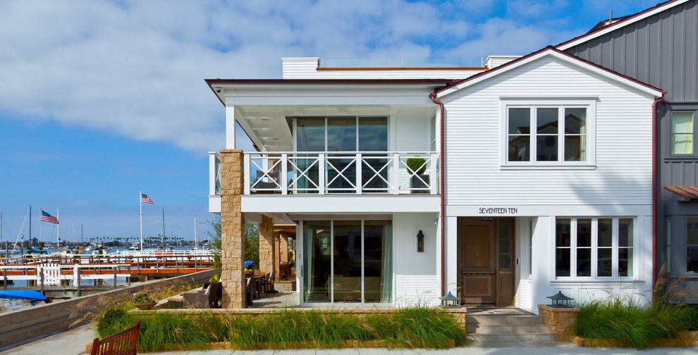 Cette photo montre une grande façade de maison blanche bord de mer à un étage.