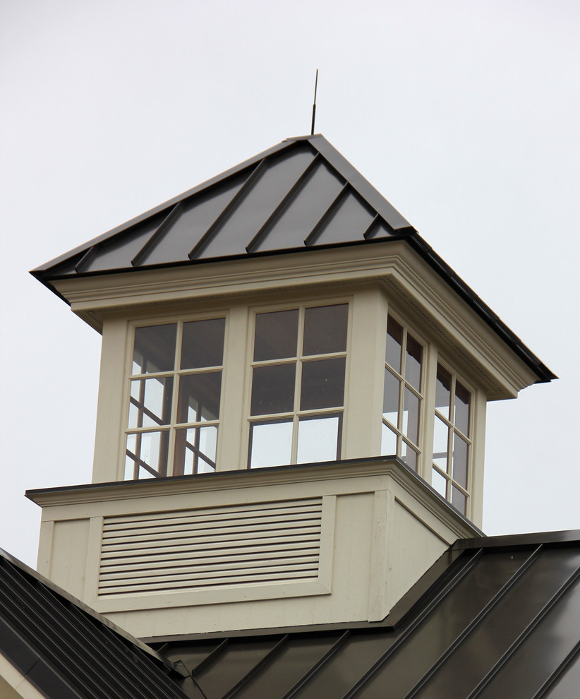 Ejemplo de fachada de casa beige de estilo de casa de campo de tamaño medio de dos plantas con revestimiento de piedra, tejado a dos aguas y tejado de metal