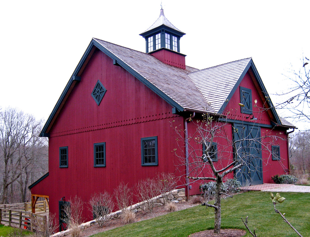 Cette image montre une façade de maison rouge de taille moyenne et à un étage avec un toit à deux pans et boîte aux lettres.