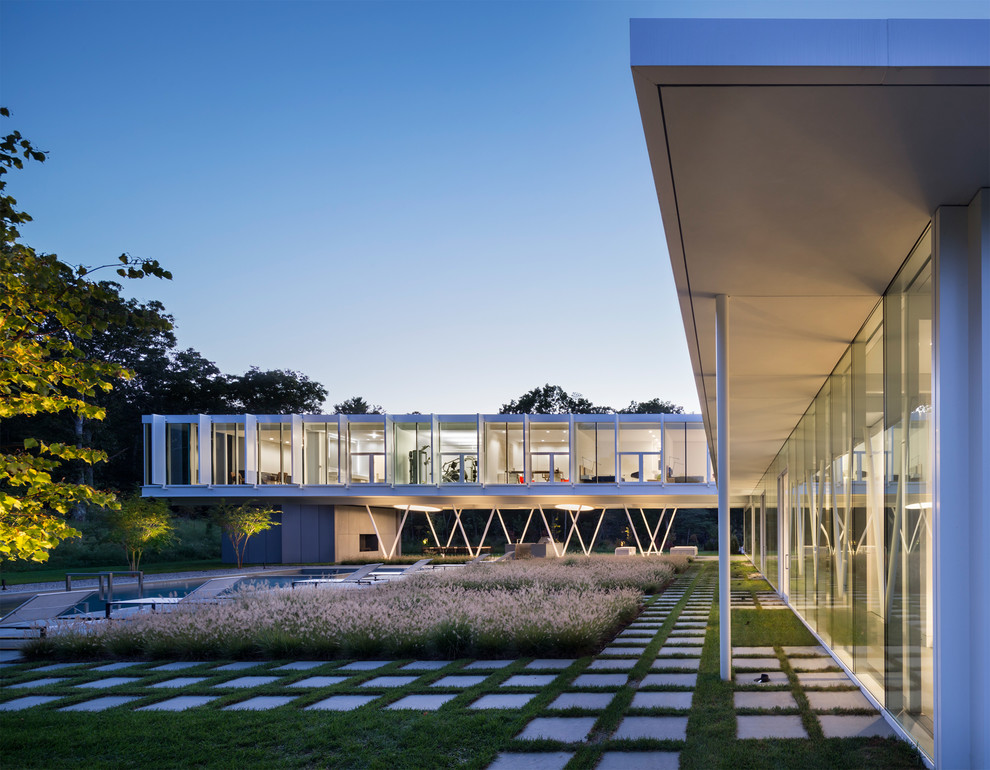 Cette image montre une grande façade de maison blanche minimaliste en verre à un étage avec un toit plat et un toit végétal.