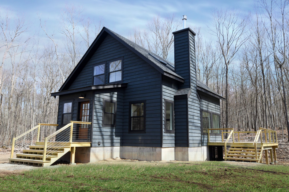 На фото: двухэтажный, деревянный, черный частный загородный дом среднего размера в стиле кантри с двускатной крышей и металлической крышей