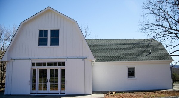 Immagine della villa piccola bianca country a due piani con rivestimento in legno, tetto a mansarda e copertura a scandole