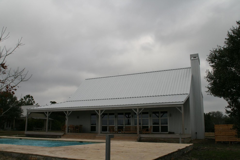 Foto della villa ampia grigia country a due piani con rivestimento in metallo e copertura in metallo o lamiera