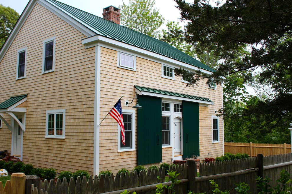 Cette photo montre une façade de maison beige éclectique de taille moyenne et à un étage avec un revêtement en vinyle, un toit à deux pans et un toit en métal.