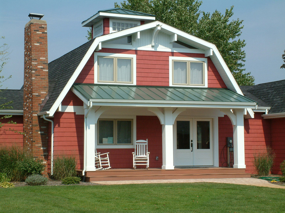 На фото: двухэтажный, красный дом в стиле кантри с облицовкой из винила