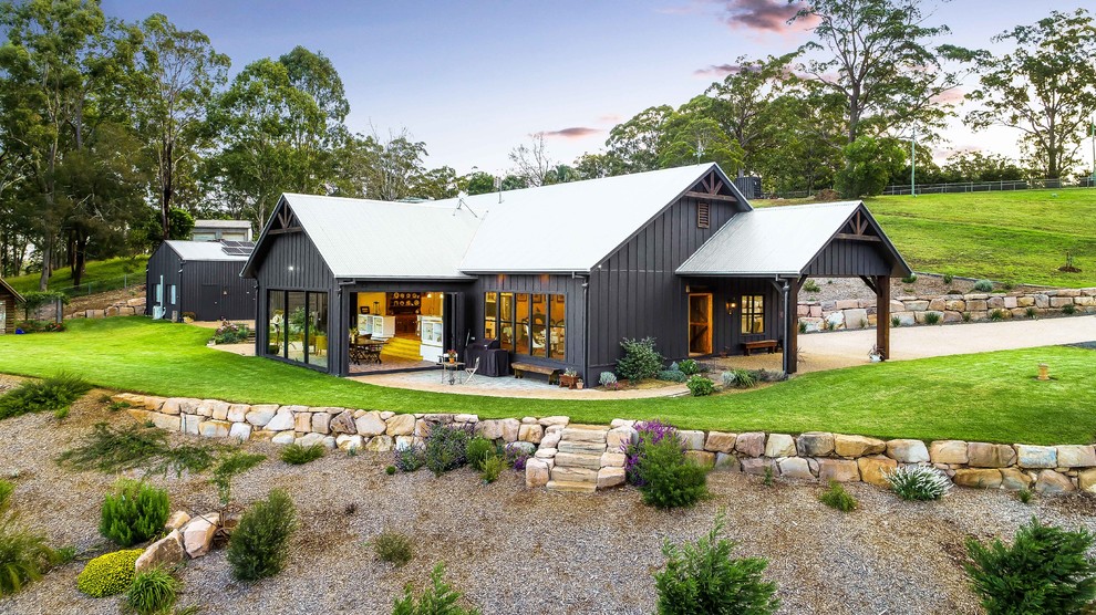 Idée de décoration pour une grande façade de maison noire champêtre de plain-pied avec un toit en appentis et un toit en métal.