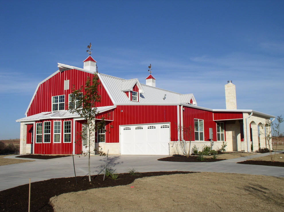 Cette image montre une très grande façade de grange rénovée rouge à un étage avec un revêtement mixte et un toit de Gambrel.