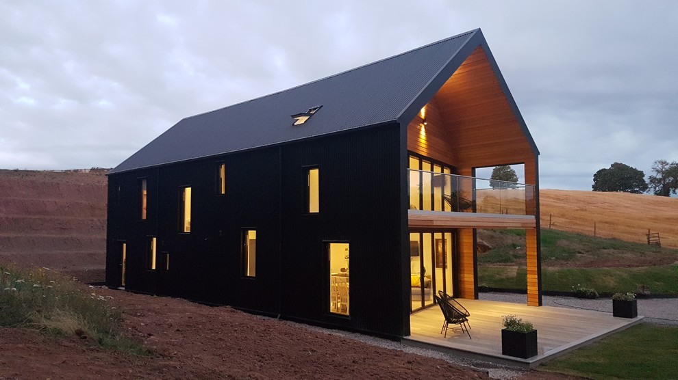 Свежая идея для дизайна: двухэтажный, черный частный загородный дом среднего размера в современном стиле с облицовкой из цементной штукатурки и двускатной крышей - отличное фото интерьера