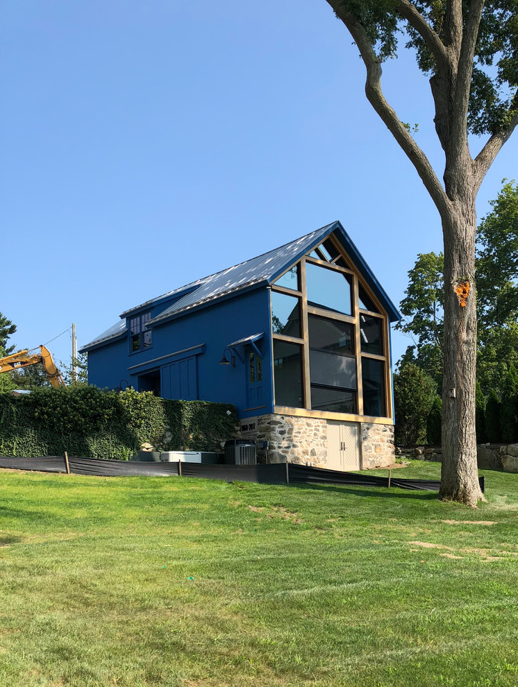 Aménagement d'une façade de maison bleue contemporaine en bois de taille moyenne et à un étage avec un toit à deux pans et un toit en métal.