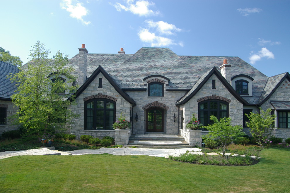 Photo of an expansive and gey classic two floor detached house in Chicago with stone cladding, a hip roof and a tiled roof.