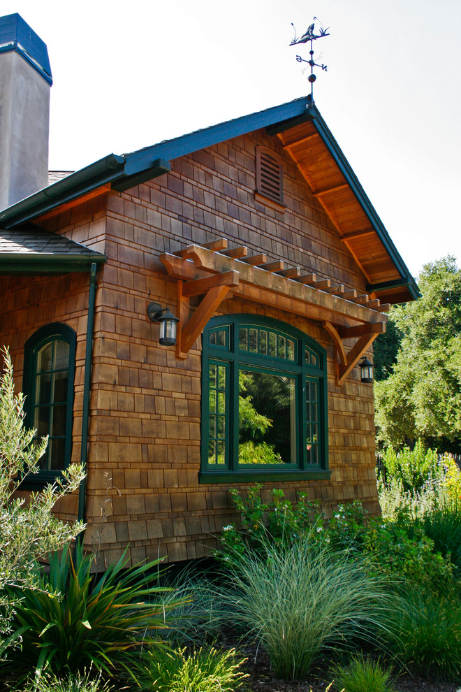 Immagine della facciata di una casa grande marrone rustica a un piano con rivestimento in legno e tetto a capanna