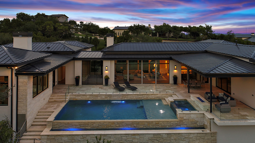 Large trendy white one-story stone house exterior photo in Austin with a metal roof