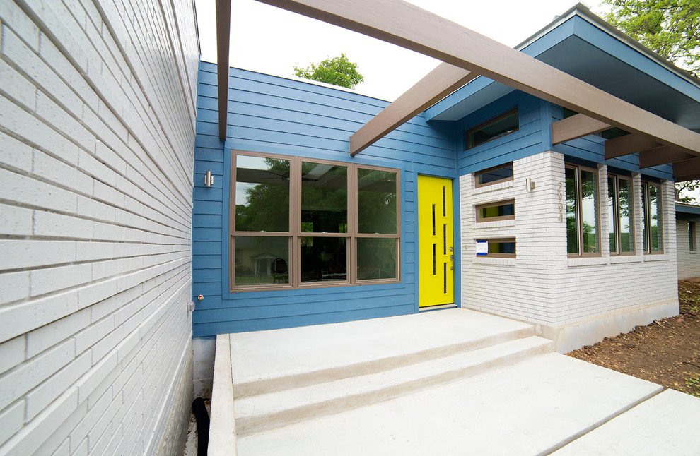 Foto på ett mellanstort funkis blått hus, med allt i ett plan och blandad fasad