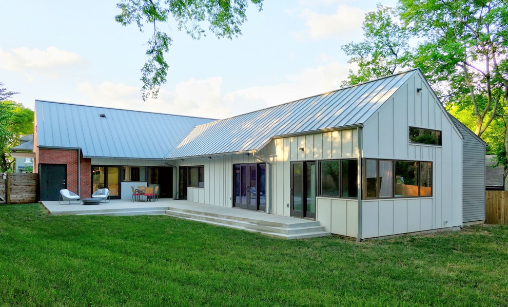 Idée de décoration pour une façade de maison blanche minimaliste en panneau de béton fibré de plain-pied avec un toit à deux pans et un toit en métal.