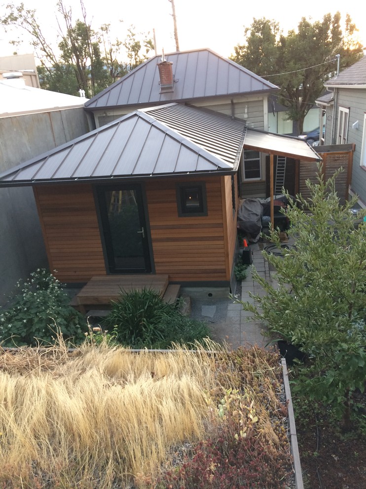Immagine della villa piccola arancione eclettica a un piano con rivestimento in legno, tetto a padiglione e copertura in metallo o lamiera