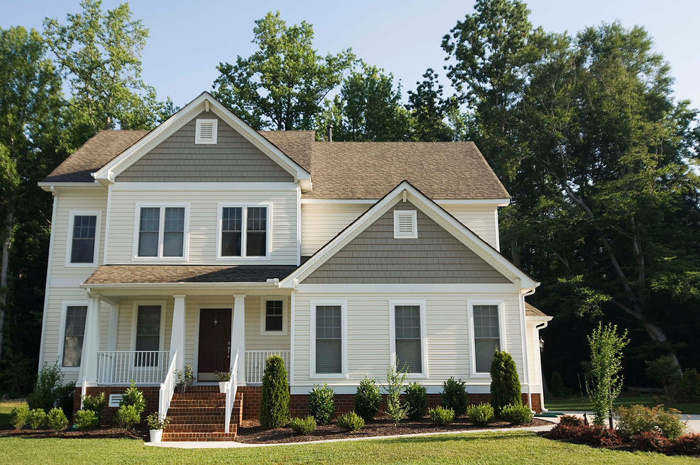 Cette image montre une façade de maison jaune traditionnelle de taille moyenne et à un étage avec un revêtement en vinyle et un toit de Gambrel.