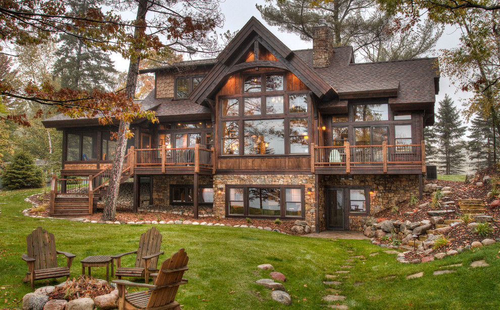 На фото: большой, деревянный, коричневый, двухэтажный дом в стиле рустика с двускатной крышей для охотников с