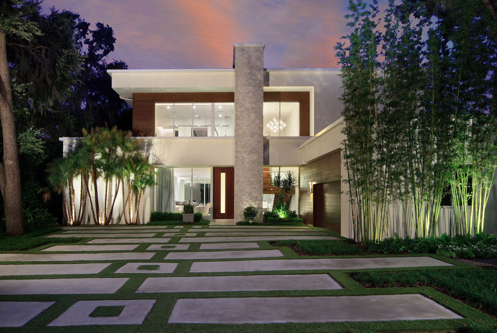 На фото: двухэтажный, белый частный загородный дом в современном стиле с облицовкой из цементной штукатурки и плоской крышей