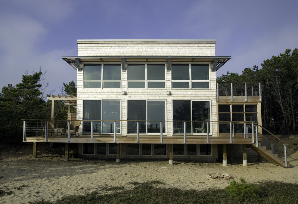 This is an example of a medium sized beach style two floor house exterior in Boston with wood cladding.