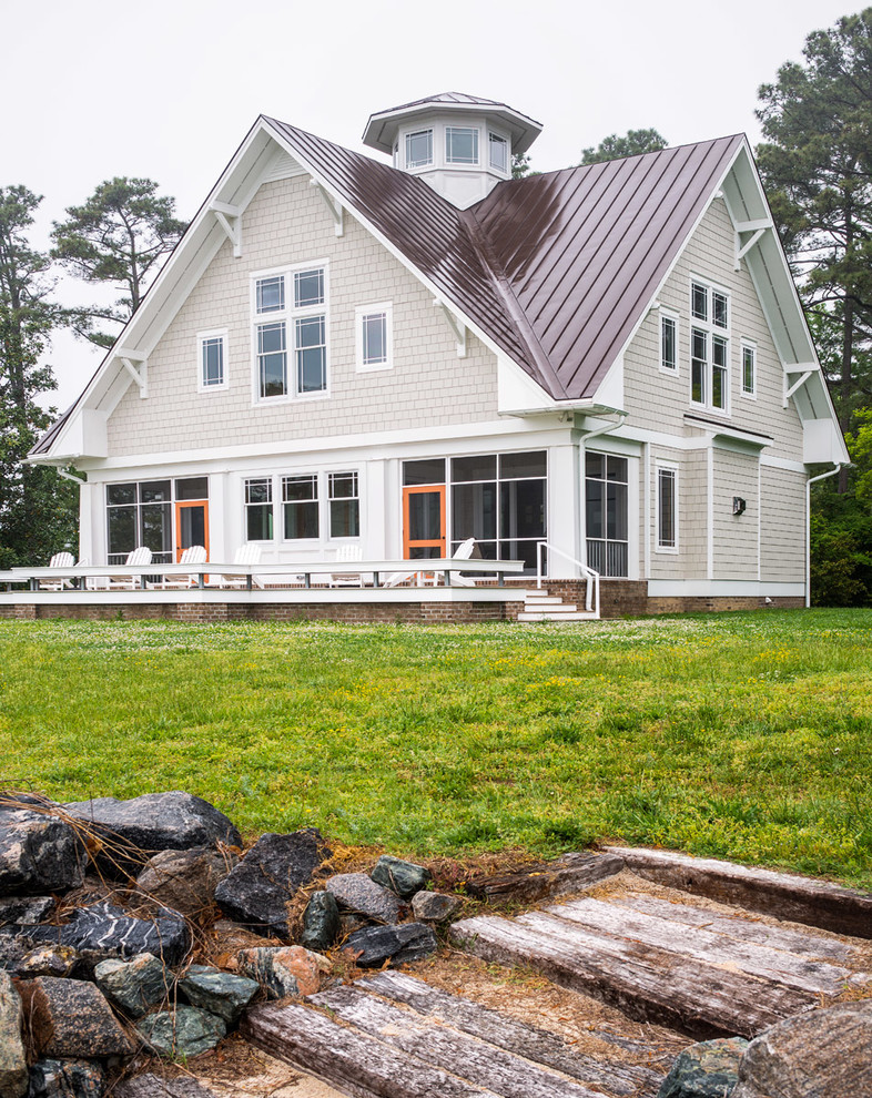 Large coastal beige two-story wood house exterior idea in Richmond with a clipped gable roof and a metal roof