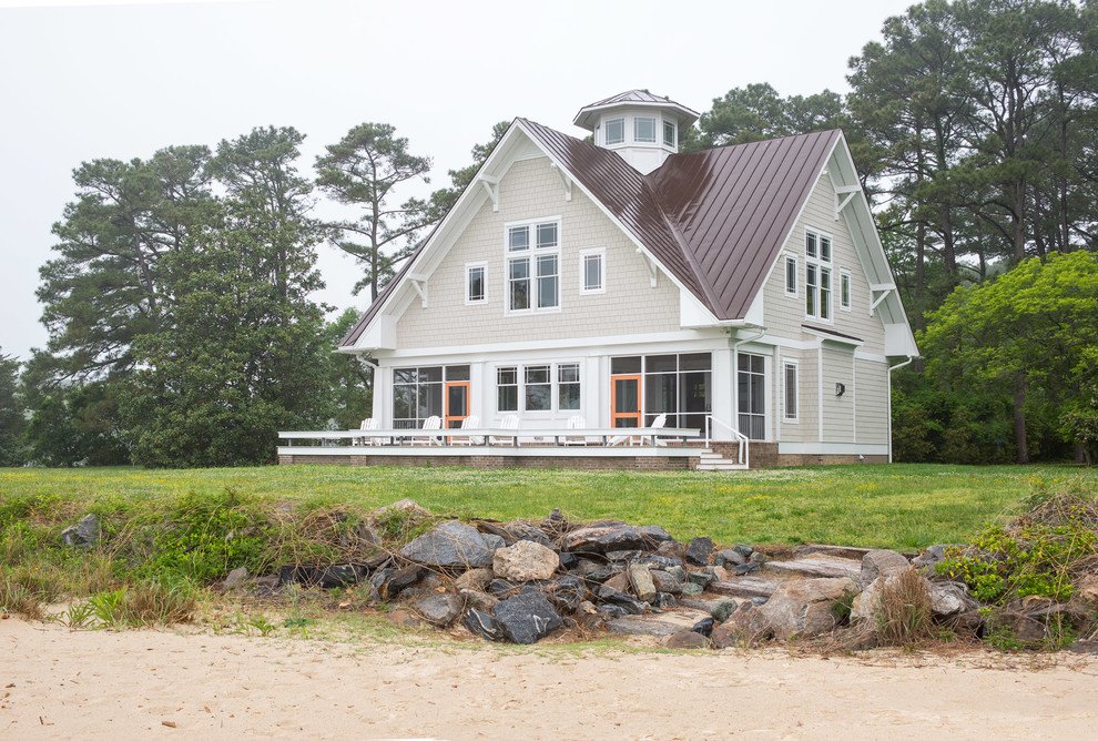 Diseño de fachada de casa beige costera grande de dos plantas con revestimiento de madera, tejado a la holandesa y tejado de metal