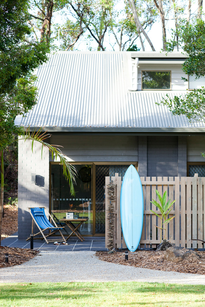 Photo of a gey beach style two floor house exterior in Brisbane with a pitched roof.