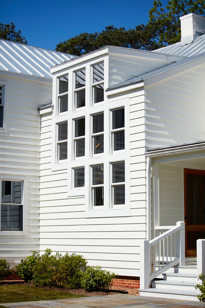 Imagen de fachada de casa blanca de dos plantas con revestimiento de vinilo y tejado de metal