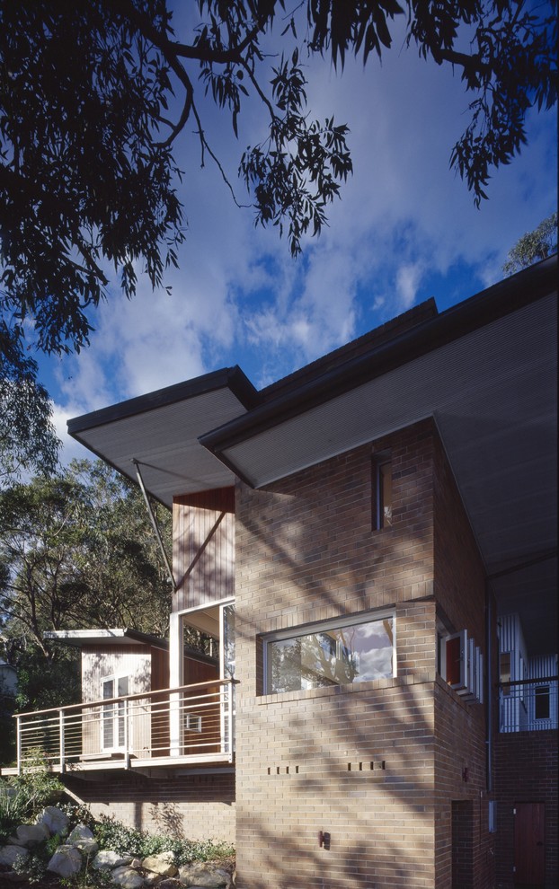 Example of a mid-sized trendy brown two-story brick flat roof design in Sydney