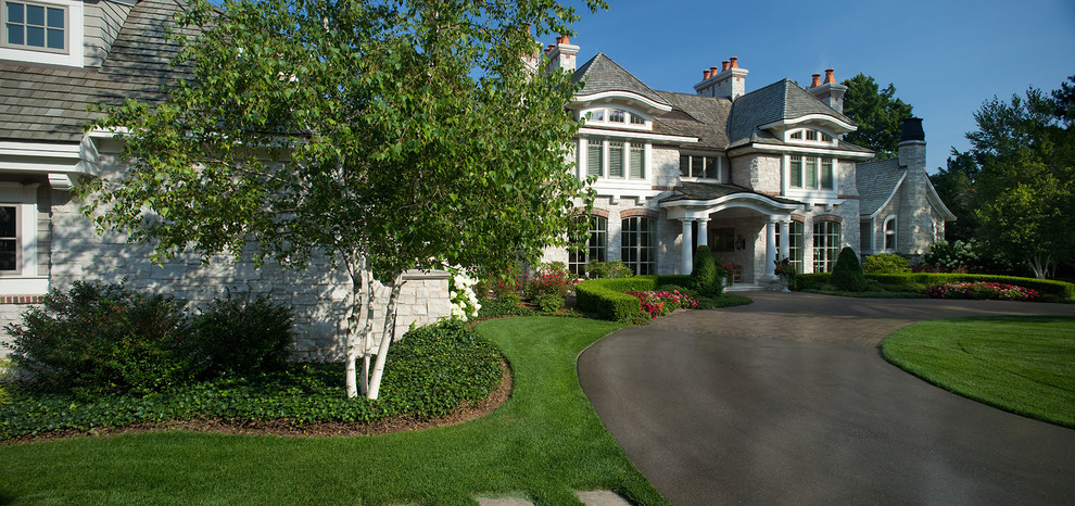 Пример оригинального дизайна: огромный, трехэтажный, серый дом в классическом стиле с облицовкой из камня