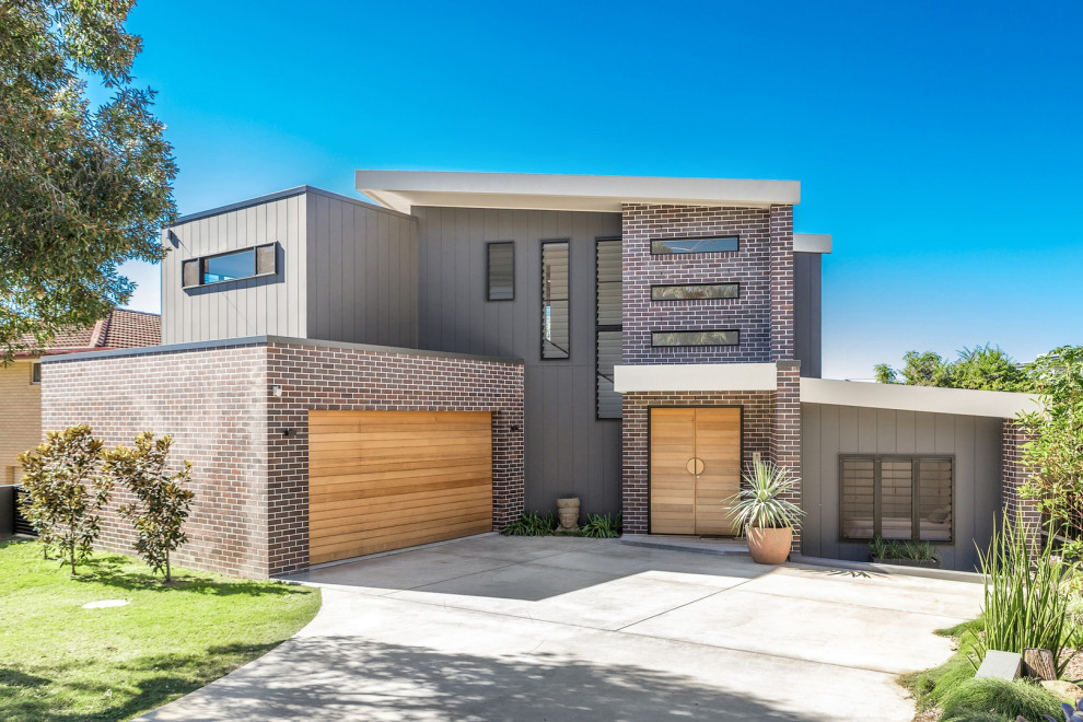 Diseño de fachada de casa gris contemporánea de dos plantas con revestimientos combinados y tejado de un solo tendido