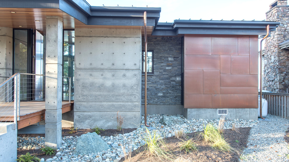 Ispirazione per la facciata di una casa piccola grigia moderna con rivestimento in cemento e copertura in metallo o lamiera