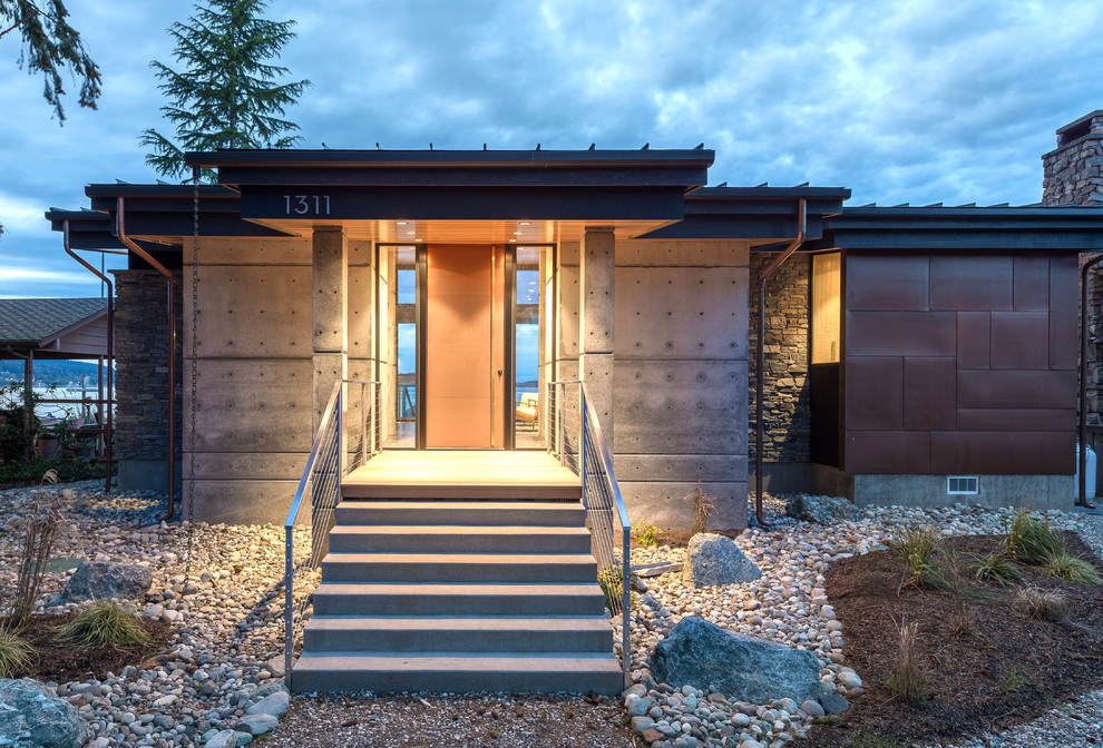 Aménagement d'une petite façade de maison grise moderne en béton de plain-pied avec un toit en appentis et un toit en métal.