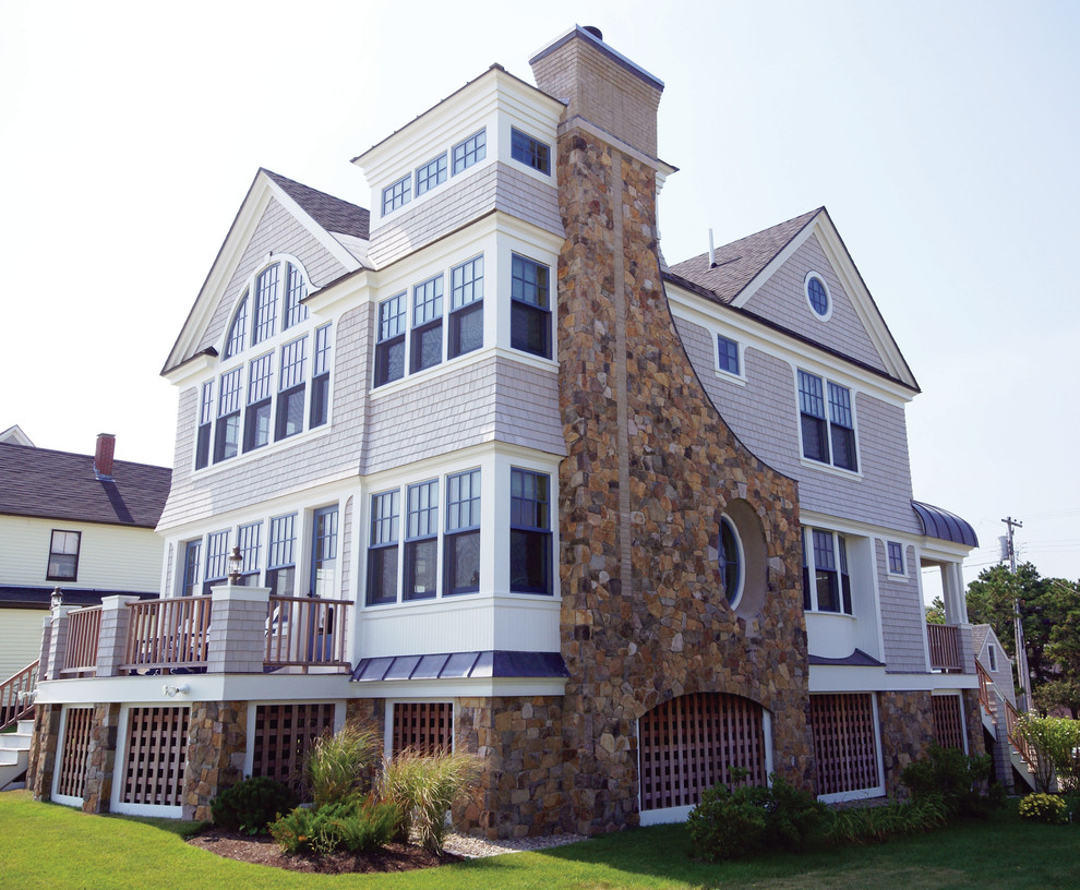 Aménagement d'une façade de maison grise bord de mer en pierre à un étage et de taille moyenne avec un toit à deux pans.