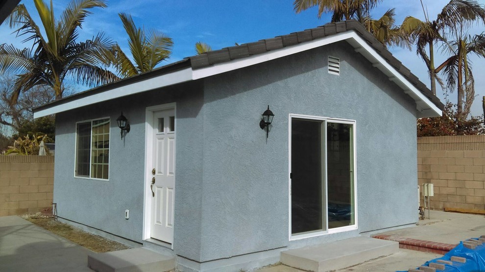 Diseño de fachada de casa azul marinera pequeña de una planta con revestimiento de estuco, tejado a dos aguas y tejado de teja de madera