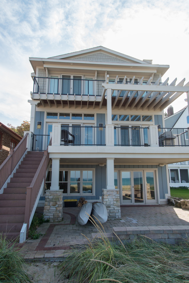 Example of a large beach style blue three-story wood house exterior design in Chicago with a shingle roof