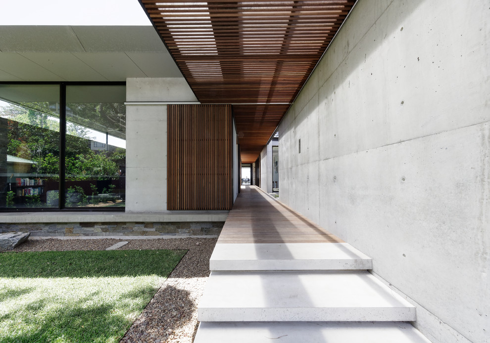 Cette image montre une façade de maison grise minimaliste en béton de taille moyenne et à un étage avec un toit plat et un toit en métal.