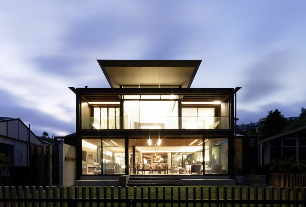 Inspiration pour une façade de maison grise minimaliste en béton de taille moyenne et à un étage avec un toit plat et un toit en métal.
