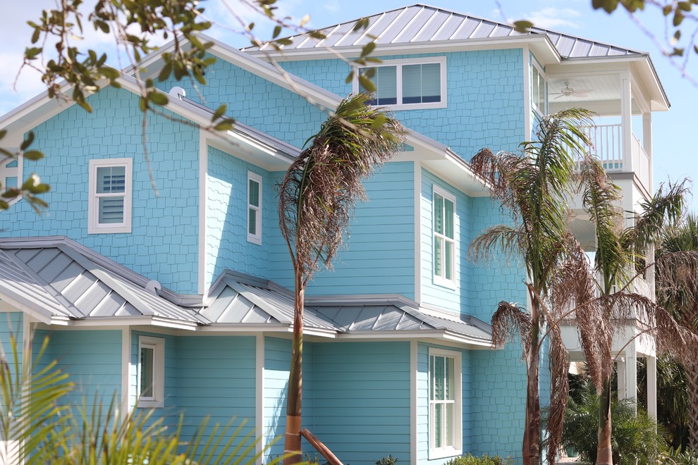 Foto della villa grande blu stile marinaro a tre piani con rivestimento in legno, tetto a padiglione e copertura in metallo o lamiera