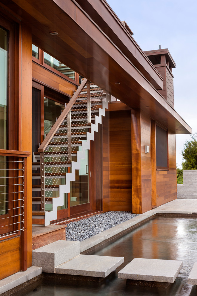 Modelo de fachada de casa marrón marinera grande de una planta con revestimiento de madera, tejado plano y escaleras