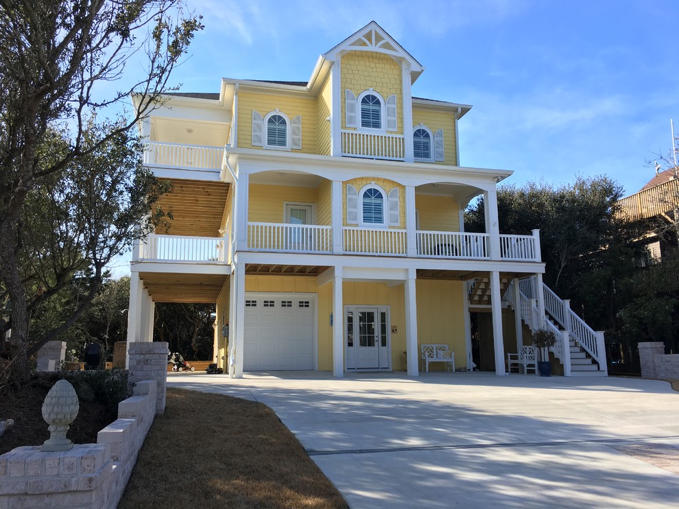 Huge coastal yellow three-story wood gable roof idea in Other