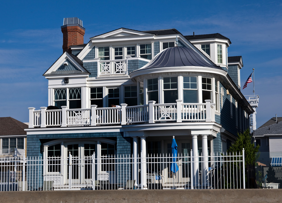 Foto de fachada azul marinera grande de tres plantas con revestimiento de madera y tejado a dos aguas