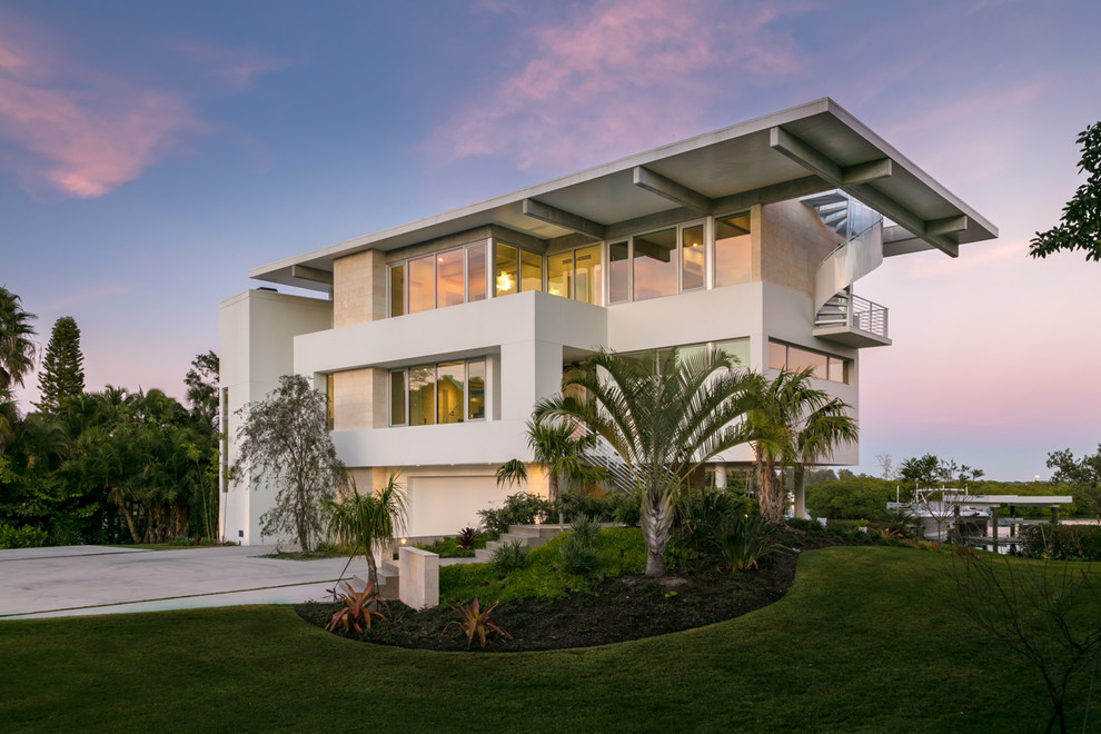 This is an example of a large and white coastal detached house in Tampa with three floors, mixed cladding and a flat roof.