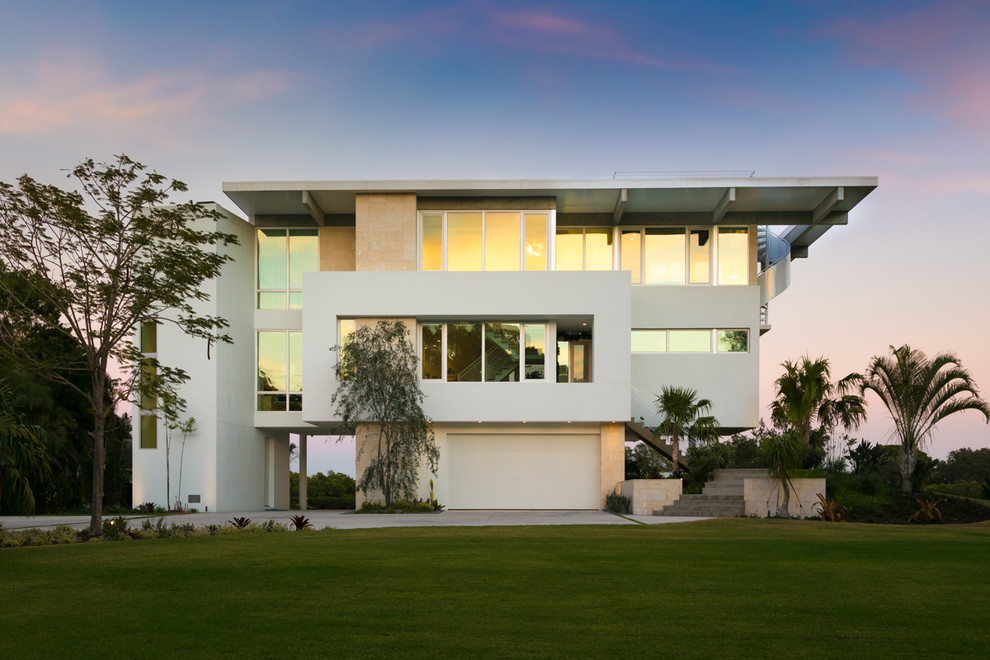 Ejemplo de fachada de casa blanca costera grande de tres plantas con revestimientos combinados y tejado plano