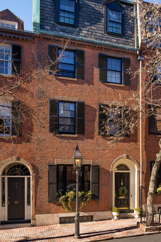Large and red traditional brick terraced house in Boston with three floors and a mansard roof.